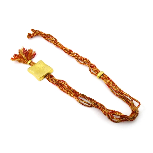 709 - A necklace of twisted orange and golden coloured thread form with gilt metal sliders and pendant mar... 