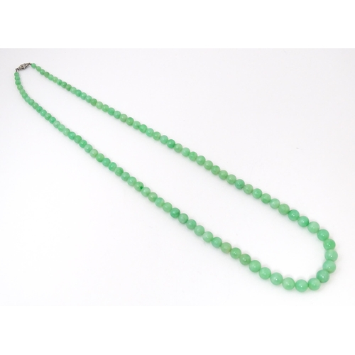 722 - A necklace of graduated green jade beads  with white metal clasp set with diamonds. Approx 28