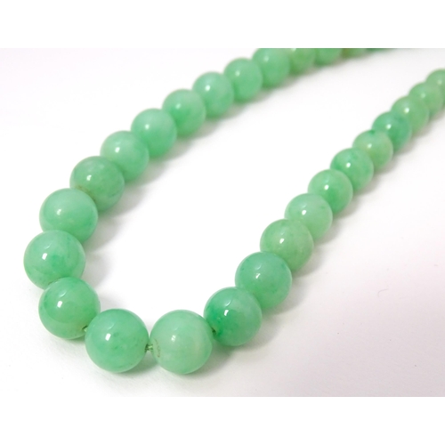 722 - A necklace of graduated green jade beads  with white metal clasp set with diamonds. Approx 28