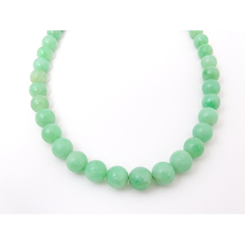 722 - A necklace of graduated green jade beads  with white metal clasp set with diamonds. Approx 28