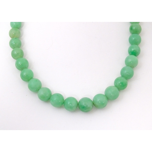 722 - A necklace of graduated green jade beads  with white metal clasp set with diamonds. Approx 28