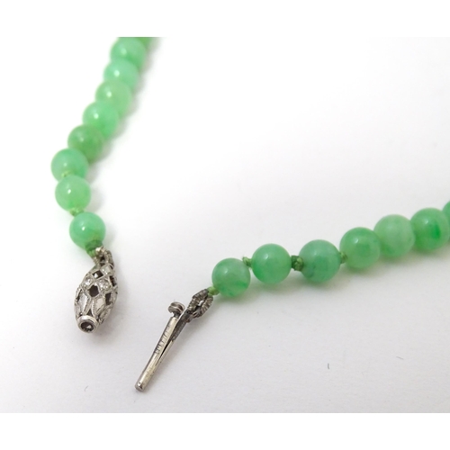 722 - A necklace of graduated green jade beads  with white metal clasp set with diamonds. Approx 28