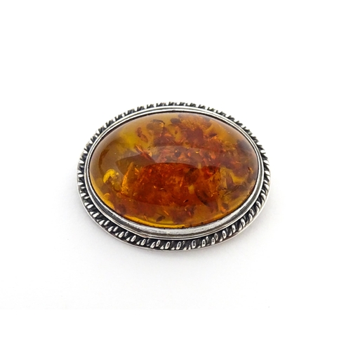 724 - A white metal ring set with amber, together with an oval brooch. Ring size approx M.  (2)