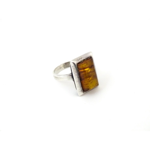 724 - A white metal ring set with amber, together with an oval brooch. Ring size approx M.  (2)