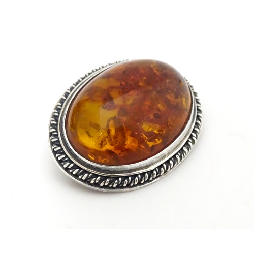 724 - A white metal ring set with amber, together with an oval brooch. Ring size approx M.  (2)