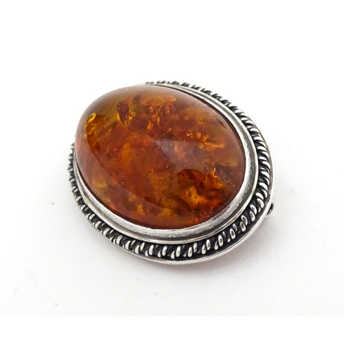 724 - A white metal ring set with amber, together with an oval brooch. Ring size approx M.  (2)