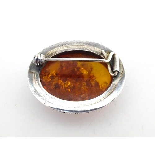 724 - A white metal ring set with amber, together with an oval brooch. Ring size approx M.  (2)