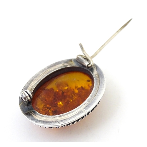 724 - A white metal ring set with amber, together with an oval brooch. Ring size approx M.  (2)