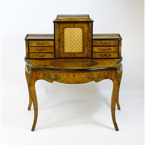 A 19thC burr walnut Bonheur du jour, with a brass gallery surmounting the two banks of three short drawers and panelled cupboard to the centre, the serpentine shaped top inset with an oval writing section, the base having a frieze drawer raised on cabriole legs. The structure decoratively inlaid with satinwood marquetry decoration and having gilt metal mounts throughout. 45" wide x 22" deep x 46" high.