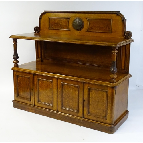 1598 - A late 19thC oak buffet, with a shaped upstand, carved edges, burr panels and carved roundel to the ... 