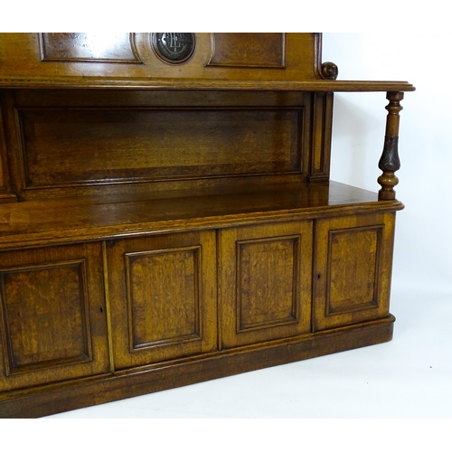 1598 - A late 19thC oak buffet, with a shaped upstand, carved edges, burr panels and carved roundel to the ... 