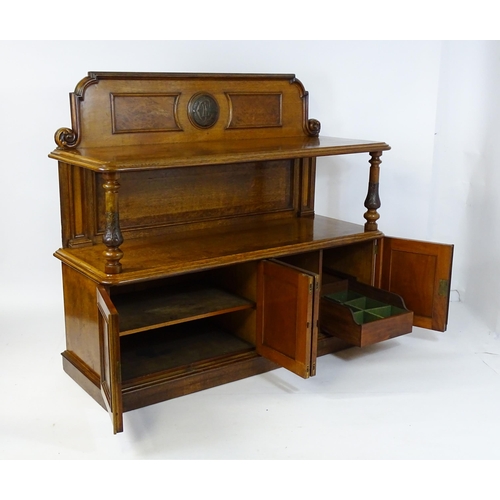 1598 - A late 19thC oak buffet, with a shaped upstand, carved edges, burr panels and carved roundel to the ... 