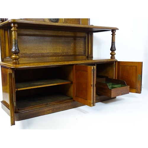 1598 - A late 19thC oak buffet, with a shaped upstand, carved edges, burr panels and carved roundel to the ... 