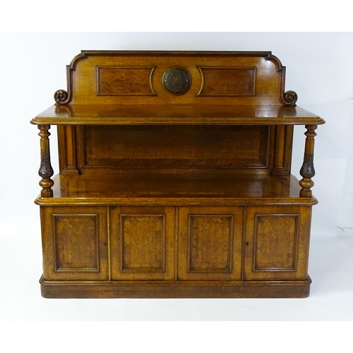 1598 - A late 19thC oak buffet, with a shaped upstand, carved edges, burr panels and carved roundel to the ... 