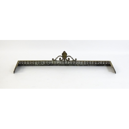 1367 - A late 19thC brass fender with a pierced, moulded frame and a female mask flanked by scrolled tendri... 