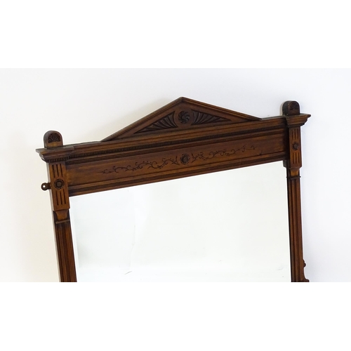 1610 - An Aesthetic movement mahogany mirror with a carved pointed pediment above fluted and floral carving... 