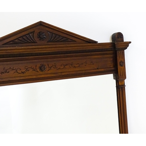 1610 - An Aesthetic movement mahogany mirror with a carved pointed pediment above fluted and floral carving... 