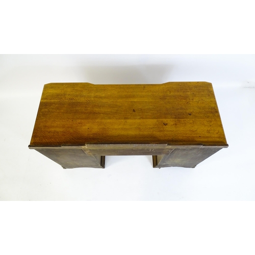 1621 - An Art Deco oak desk / dressing table with a shaped upstand, inverted breakfront top and fluted pila... 