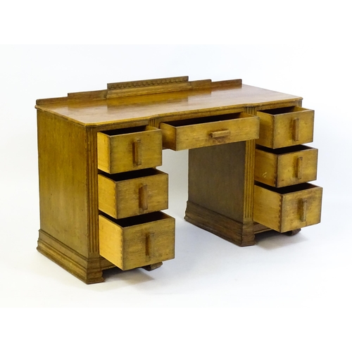 1621 - An Art Deco oak desk / dressing table with a shaped upstand, inverted breakfront top and fluted pila... 