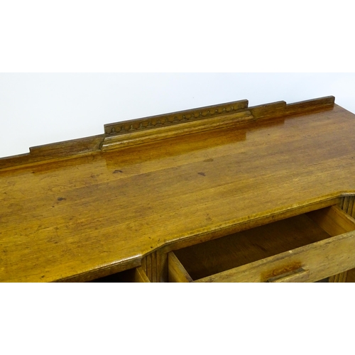 1621 - An Art Deco oak desk / dressing table with a shaped upstand, inverted breakfront top and fluted pila... 