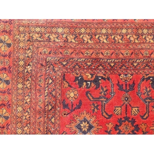 1493 - Carpet / Rug : A large red ground carpet with central repeated floral motifs with banded borders of ... 