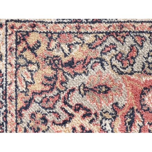 1506 - Carpet / Rug : A salmon pink ground woollen rug with floral and foliate detail, further repeated to ... 