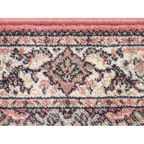 1506 - Carpet / Rug : A salmon pink ground woollen rug with floral and foliate detail, further repeated to ... 