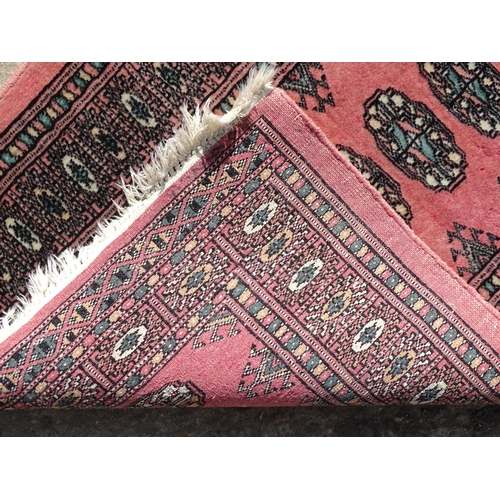 1507 - Carpet / Rug: A salmon pink ground rug with central medallions, with geometric borders. Approx. 35