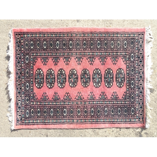 1507 - Carpet / Rug: A salmon pink ground rug with central medallions, with geometric borders. Approx. 35