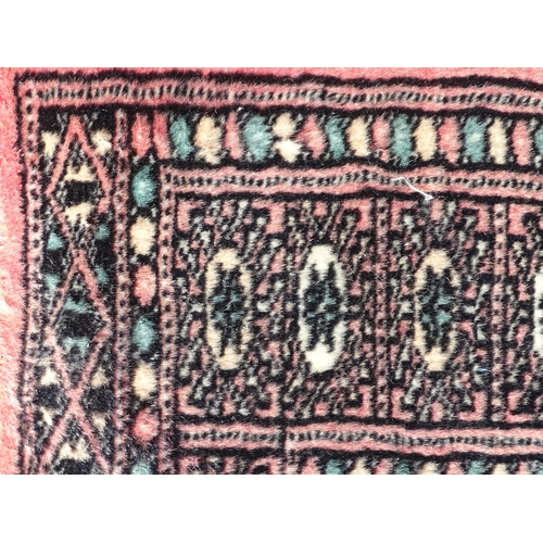 1507 - Carpet / Rug: A salmon pink ground rug with central medallions, with geometric borders. Approx. 35