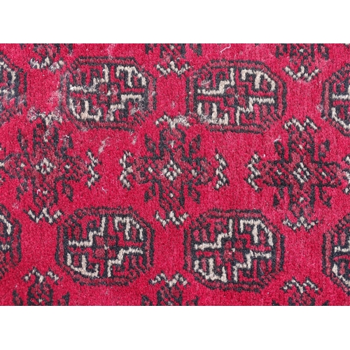 1514 - Carpet / Rug : A red ground runner with repeated geometric motifs and medallions. Approx. 115