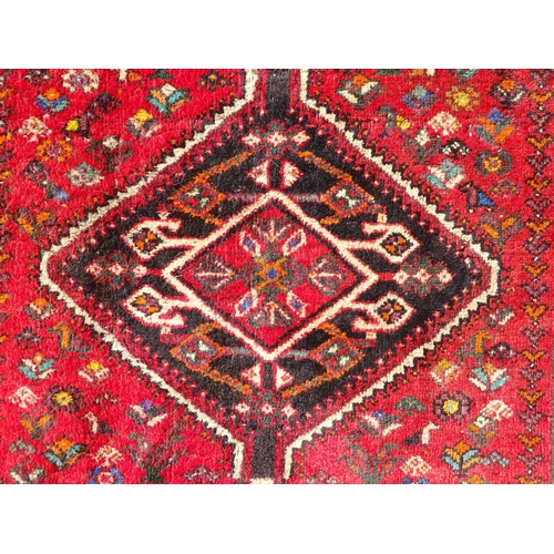 1518 - Carpet / Rug : A red ground rug decorated with central vignette bordered by stylised floral and foli... 