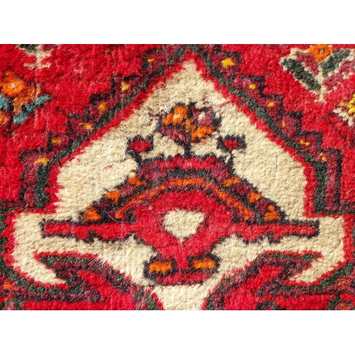 1518 - Carpet / Rug : A red ground rug decorated with central vignette bordered by stylised floral and foli... 