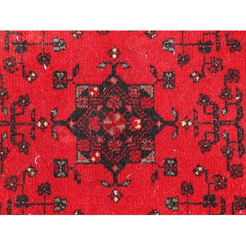 1526 - Carpet / Rug : A red ground rug with stylised floral and foliate detail.  29