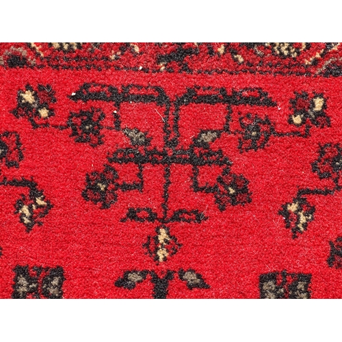 1526 - Carpet / Rug : A red ground rug with stylised floral and foliate detail.  29