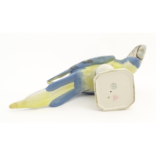 165 - A Royal Dux model of a Macaw bird / Parrot with blue, green and yellow feathers perched on a finial.... 