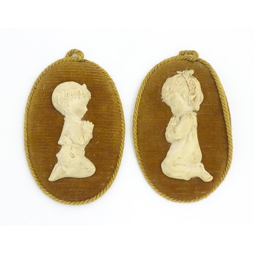 200 - Two Capodimonte plaques depicting children at prayer, upon an oval cushioned backing. Figures approx... 