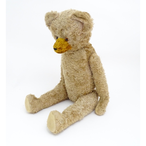 1428 - Toy: A large early 20thC straw filled mohair teddy bear, with stitched nose and mouth, pad paws and ... 