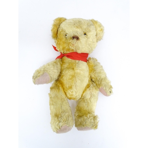 1446 - Toy: A 20thC plush teddy bear with scrolled nose, pad paws and articulated limbs. Approx. 11