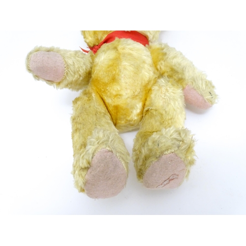 1446 - Toy: A 20thC plush teddy bear with scrolled nose, pad paws and articulated limbs. Approx. 11