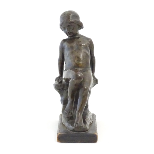 1099 - An early 20thC cast figure depicting a young boy on a rock plinth. Indistinctly signed to base Flore... 