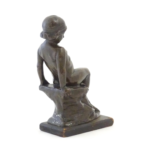 1099 - An early 20thC cast figure depicting a young boy on a rock plinth. Indistinctly signed to base Flore... 