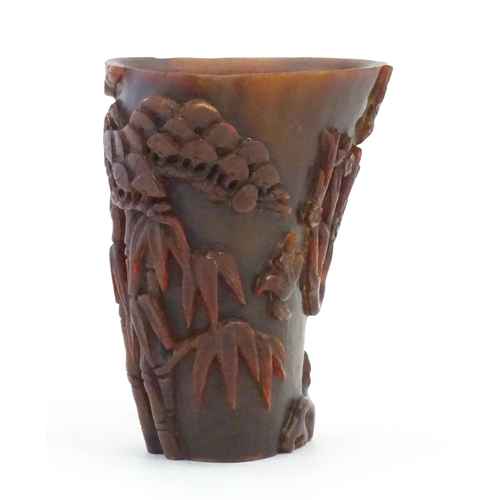 1118 - An Oriental carved horn libation cup decorated with birds, bamboo, flowering trees, etc. Approx. 5