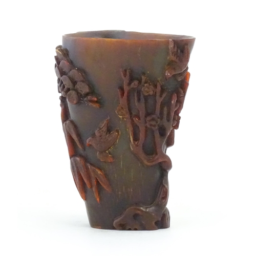 1118 - An Oriental carved horn libation cup decorated with birds, bamboo, flowering trees, etc. Approx. 5