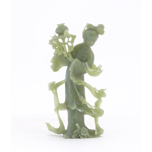 1123 - An Oriental jade coloured hardstone carving modelled as a woman with flowing drapery and flowers hol... 