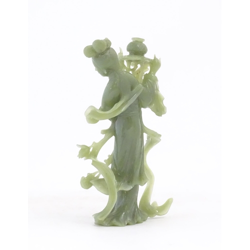 1123 - An Oriental jade coloured hardstone carving modelled as a woman with flowing drapery and flowers hol... 