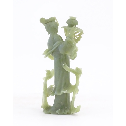 1123 - An Oriental jade coloured hardstone carving modelled as a woman with flowing drapery and flowers hol... 