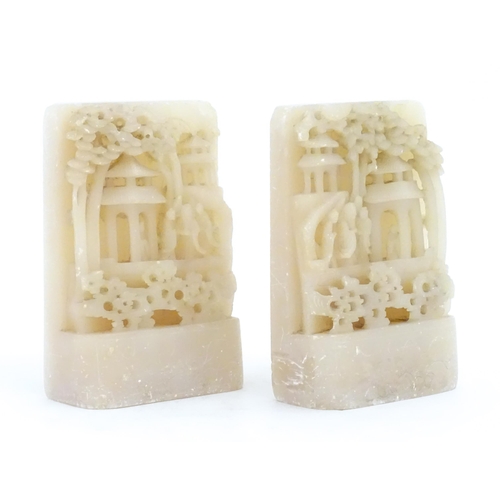 1126 - A pair of Oriental carved soapstone bookends depicting figures, pagoda style buildings and trees. Ap... 