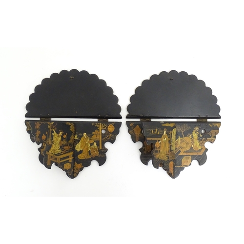 1134 - A pair of Oriental lacquered papier mache folding wall brackets decorated with figures in gardens an... 