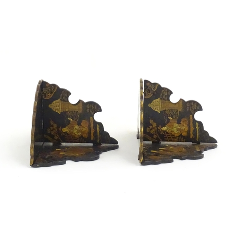 1134 - A pair of Oriental lacquered papier mache folding wall brackets decorated with figures in gardens an... 